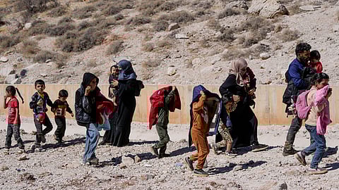 Families cross into Syria on foot, through a crater caused by Israeli airstrikes aiming to block the Beirut-Damascus highway at the Masnaa crossing, in the eastern Bekaa Valley, Lebanon, Saturday, Oct. 5, 2024.