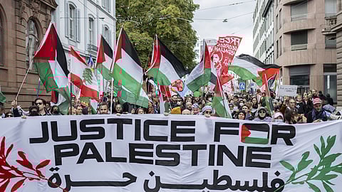 Protesters hold placards and Palestinian flags during a rally in support of the Palestinian people, in Basel, Switzerland, Saturday, Oct. 5, 2024.
