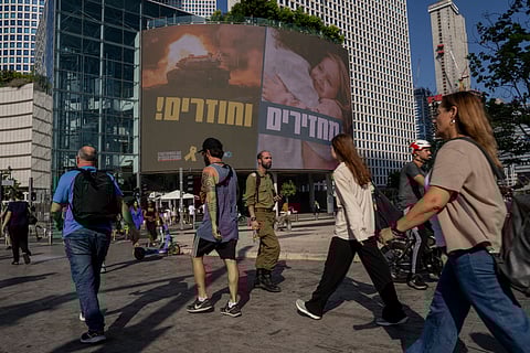 People pass by a sign calling for the release of hostages held in the Gaza Strip by Hamas for nearly a year, in Tel Aviv, Israel, Monday, Sept. 10, 2024.