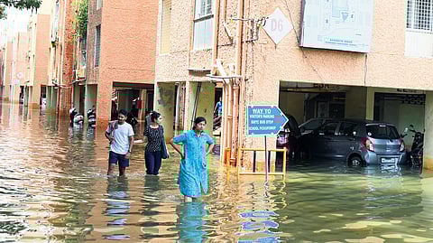 Residents of Kendriya Vihar apartment complex in Yelahanka wade through knee-deep water on Sunday. Below: The collapsed compound wall and part of a house in Binnypet