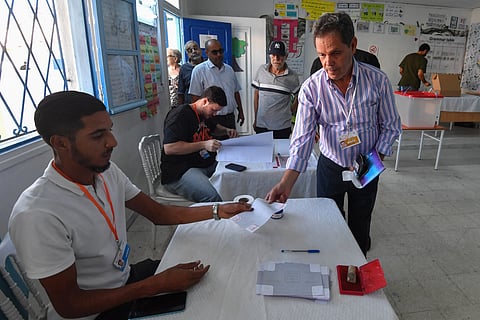 A Tunisian receives a ballot ahead of casting his vote in the presidential election at a polling station in Tunis on October 6, 2024.