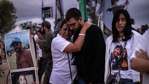 Two people embrace as relatives and supporters of Israelis killed in the October 7 Hamas attack attend a ceremony at the Nova memorial near Kibbutz Reim