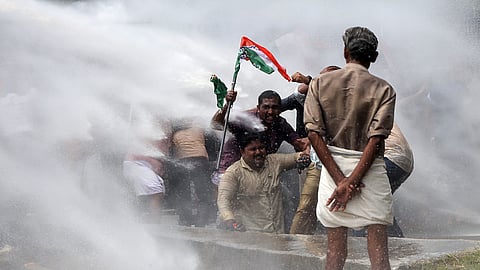 UDYF activists huddle together as police use water cannons to disperse them during their protest march to the assembly demanding the resignation of Chief Minister Pinarayi Vijayan over the ADGP-RSS meetings.