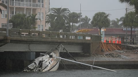 A boat damaged in Hurricane Helene rests against a bridge ahead of the arrival of Hurricane Milton.