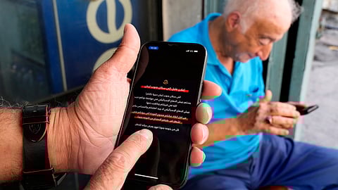 Men read mobile phone alerts telling residents of southern Lebanon not to return to their homes until further notice because of operations Israel says are targeting Hezbollah facilities in Beirut, Lebanon, Wednesday, Oct. 9, 2024.