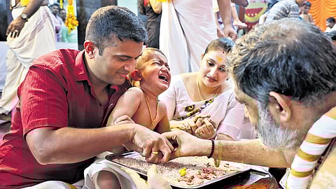 Attukal Devi Temple head priest V Muraleedharan Namboothiri introduces a child to the world of letters during the Vijayadashami celebrations at the temple
on Sunday.