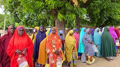 Women and villagers wait to receive food donations from the United Nations World Food Program in Damasak, northeastern Nigeria, Sunday, Oct. 6, 2024.