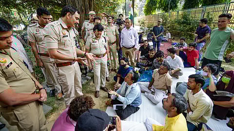 A policeman speaks with climate activist Sonam Wangchuk staging a protest demanding the inclusion of Ladakh in the Sixth Schedule of the Indian constitution, at the Ladakh Bhawan, in New Delhi, Sunday, Oct. 13, 2024.