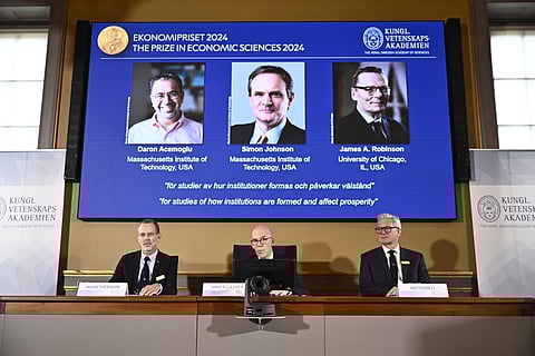Academy of Sciences permanent secretary Hans Ellegren, center, Jakob Svensson, left, and Jan Teorell, of the Nobel assembly announce the Nobel memorial prize in economics winners, Daron Acemoglu, Simon Johnson and James A Robinson, seen on screen, during a press meeting at the Royal Swedish Academy of Sciences in Stockholm, Sweden.