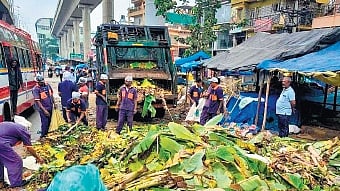BBMP workers clear waste generated during the Dasara festival at a market
