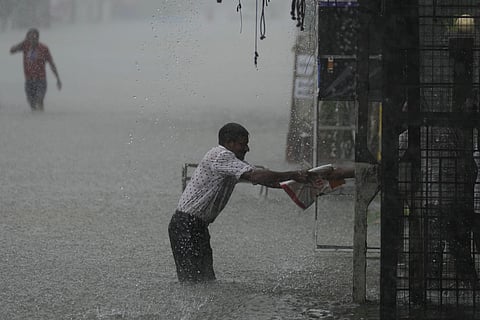A man reaches for a safe place as it rains in a flooded street in Colombo, Sri Lanka, Sunday, Oct. 13, 2024.