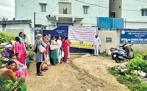 Teachers wait outside a residential school building in Warangal district on Tuesday. The building gate was locked by the owner demanding payment of rent arrears