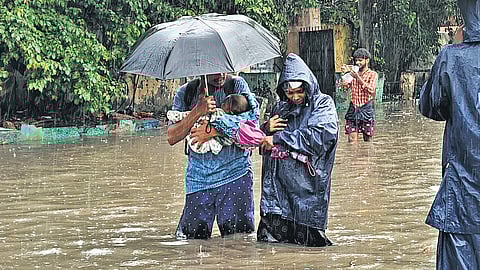 A couple carrying an infant on a water-logged road in Chennai