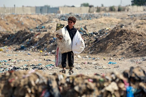 A boy carries bags after sifting through waste at a landfill in Khan Yunis in the southern Gaza Strip on October 15, 2024.