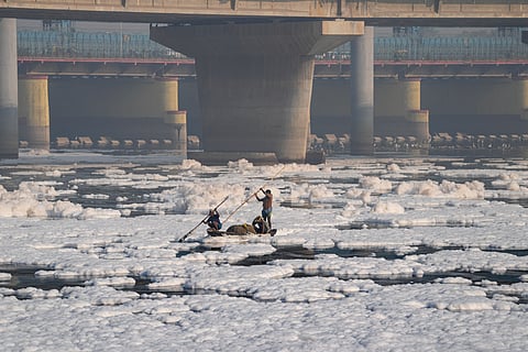 Men row a boat through the toxic foam which floats on the surface of the polluted Yamuna river, at Kalindi Kunj, in New Delhi, Saturday, Oct 19, 2024.