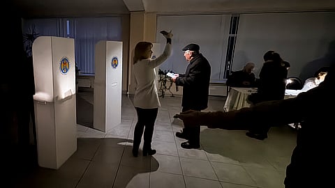 Election officials assist voters with mobile phone flashlights during a power failure in Chisinau, Moldova, Sunday, Oct. 20, 2024, during the presidential election.