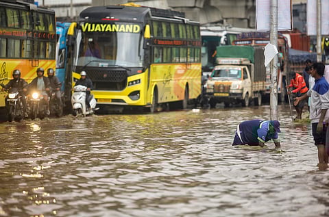 A Bruhat Bengaluru Mahanagara Palike (BBMP) worker clears the blocked drainage on a waterlogged road after rains, in Bengaluru,