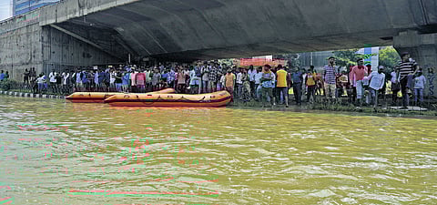 Residents of apartments take shelter under a flyover following heavy rain