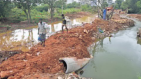 Residents walk on a damaged road between Jakkur and Thanisandra in Dr Shivaram Karanth Layout Phase 2, following heavy rain in Bengaluru