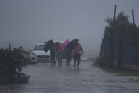 People brave through gusting wind as they walk near Dhamara fishing harbour ahead of cyclone Dana's landfall in Bhadrak district in Odisha.