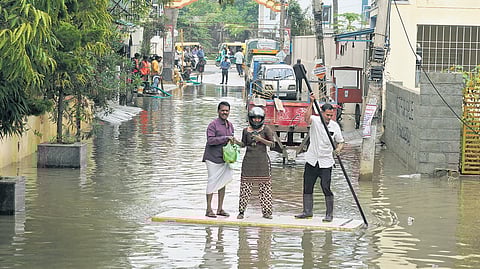 Residents use a discarded door to cross a flooded street in Bengaluru’s Horamavu