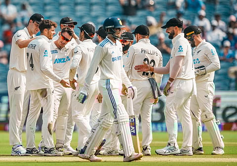 New Zealand's Mitchell Santner celebrates with teammates after taking the wicket of India's Shubman Gill on the second day of the second test cricket match between India and New Zealand.