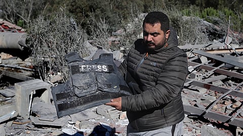 A journalist carries the flack jacket, at the site where an Israeli airstrike hit a compound housing journalists, killing three media staffers from two different news agencies according to Lebanon's state-run National News Agency, in Hasbaya village, southeast Lebanon.