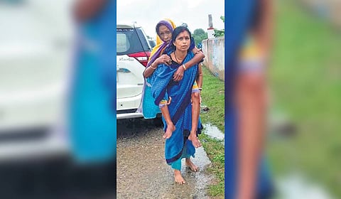 Sibani carrying an elderly woman on her back to the cyclone shelter