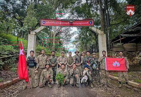 In this photo provided by Mandalay People's Defence Force, its members pose for a photograph in front of the gate of the captured army battalion in Mogok township in Mandalay region, Myanmar, on July 25, 2024.