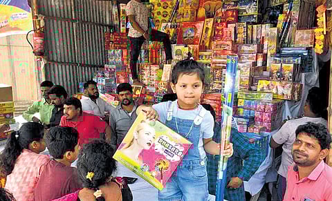 A girl is seen holding a Diwali firecracker packet at a stall.