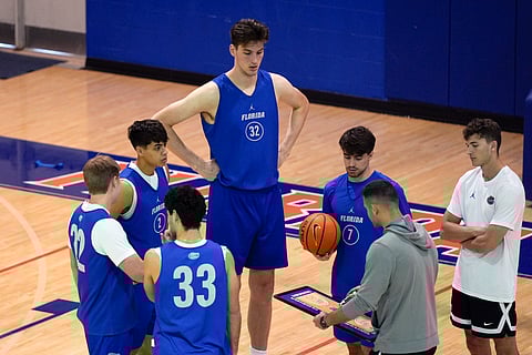 Olivier Rioux, back center, a 7-foot-9 NCAA college basketball player at Florida, gathers with coaches and teammates at the team's practice, Friday, Oct. 18, 2024, in Gainesville, Fla.