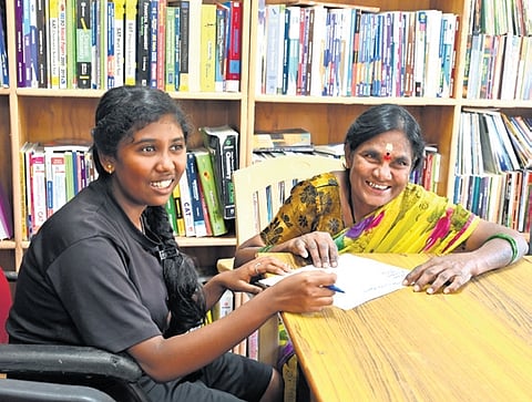 A woman being taught to read and write Kannada at the library at Neelasandra GP