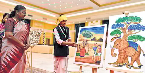 Madavi Anand Rao, a tribal artiste from Adilabad shows his paintings to President Droupadi Murmu at Rastrapati Bhavan in New Delhi