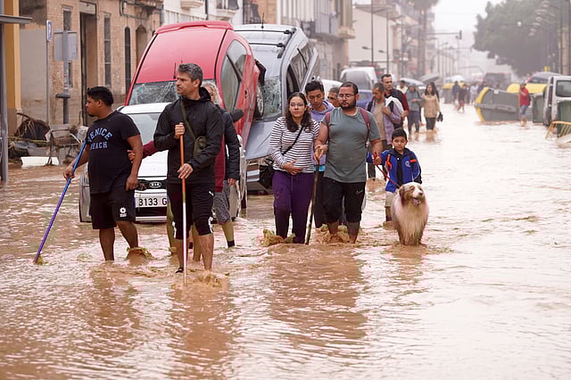 People walk through flooded streets in Valencia, Spain, Wednesday, Oct. 30, 2024.
