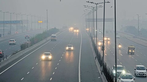 Vehicles move on a road amid low visibility due to smog early Friday morning