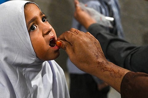 A health worker administers polio drops to a child at a school during a vaccination campaign in Lahore on October 28, 2024.