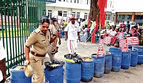 Sanitation workers block the entrance of the corporation main office with bins filled with garbage as part of the protest held on Wednesday