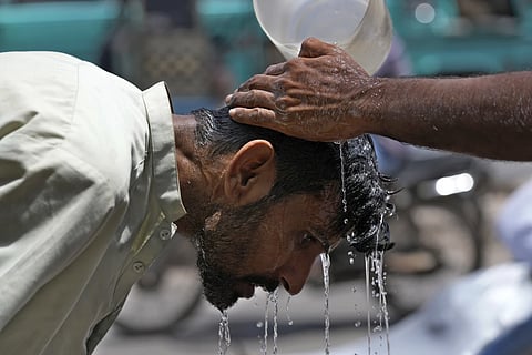 A volunteer pours water to cool a man off during a hot day in Karachi, Pakistan, May 21, 2024.