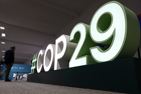 An attendee walks near a sign for the COP29 UN Climate Summit in Baku, Azerbaijan.