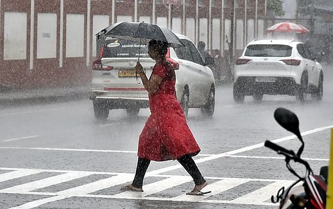 A woman crosses the road during heavy rain at ambattur