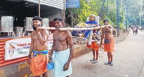 Rajagopal (front right) joins other dolly carriers from Vandiperiyar to carry an elderly woman to Sannidhanam during a previous pilgrimage season
