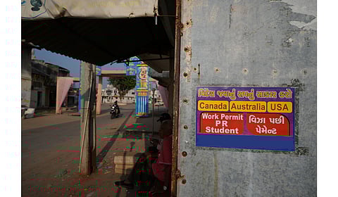 An advertising poster pasted on a shop at Dingucha village in Gandhinagar, India, Tuesday, Nov. 12, 2024. Poster reads in Gujarati "Make your dream of going abroad come true", on top and "Payment after visa".