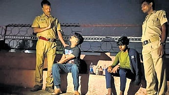 Police personnel warn youths found drinking at a public place in Rourkela