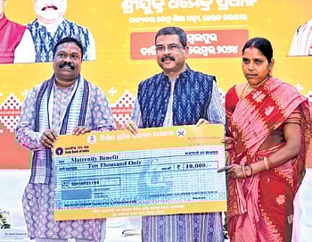 Pradhan handing over maternity benefit of Rs 10,000 to a worker
