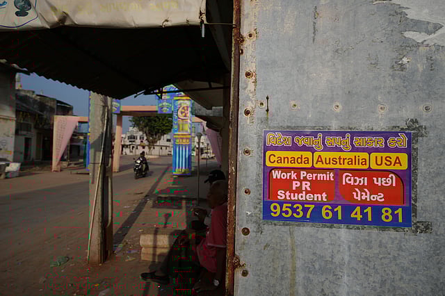 An advertising poster pasted on a shop at Dingucha village in Gandhinagar, India, Tuesday, Nov. 12, 2024. Poster reads in Gujarati "Make your dream of going abroad come true", on top and "Payment after visa".