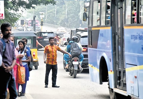 People waiting to board a bus near a bridge on Radhakrishnan Road