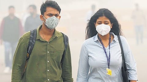 People walk wearing masks as air quality plummeted to alarming levels at the National Capital