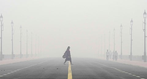 A woman crosses the Kartavya Path amid low visibility due to smog as air quality remains in 'severe' category, in New Delhi, Monday, Nov. 18, 2024.