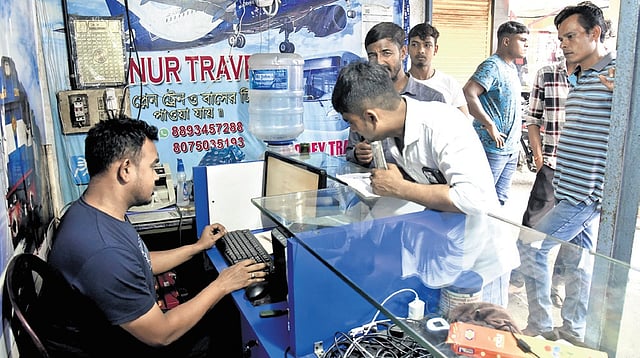 Mijanur Rahman helping a customer with transaction at Mijanur Travels, which is also a money remitting shop.