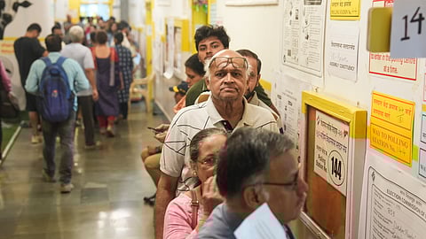 Voters wait in a queue to cast their votes at a polling station at Dadar during the Maharashtra Assembly elections, in Mumbai.